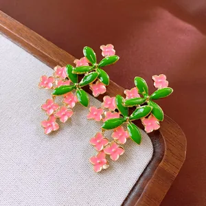 Macro view showing detailed pink enamel flower cluster stud earrings with green leaves