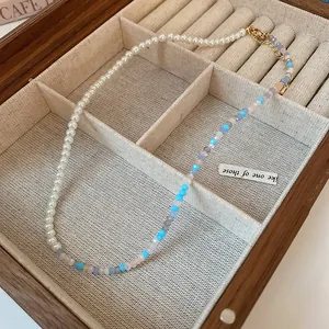Detail view of a colorful pearl beaded necklace inside a premium wooden jewelry box.