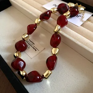 Detailed view of vintage marbled red beads and golden metal spheres necklace in a box