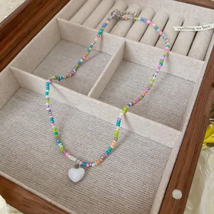 Colorful beaded necklace with white heart pendant inside a wooden jewelry box