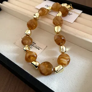 Detail of vintage style necklace with irregular marbled amber beads and gold accents