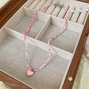 Close-up of a delicate pink beaded necklace with a heart pendant displayed in a jewelry box