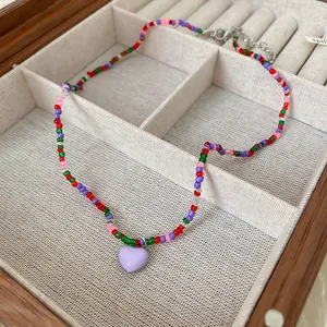 Close-up of colorful beaded necklace featuring a purple heart pendant in a box.