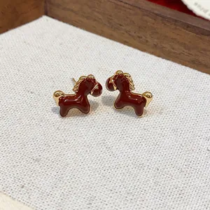 Detailed view of horse stud earrings with 18K gold plating and red enamel finish.