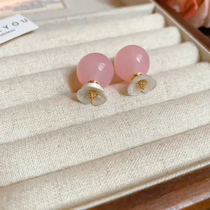 Elegant close-up of pink sphere stud earrings featuring white flower design accents