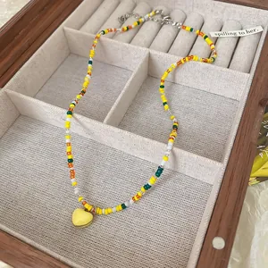 Detail shot of a vibrant colorful beaded choker necklace with a yellow heart pendant.