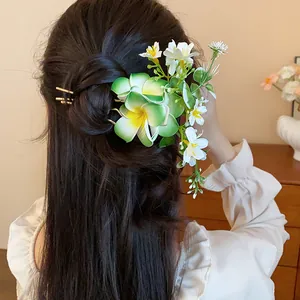 Vue détaillée de l'épingle à cheveux florale avec frangipaniers verts et fleurs.