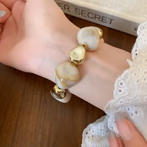 Close-up shot of irregular marbled beaded fashion jewelry on a wrist with lace details