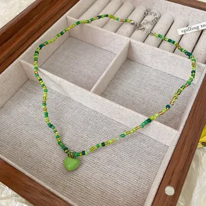 Detailed view of a handmade green beaded necklace featuring a vibrant heart pendant.