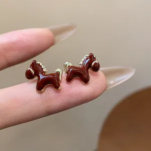 Macro view of cute brown enamel horse stud earrings with elegant 18K gold plating.