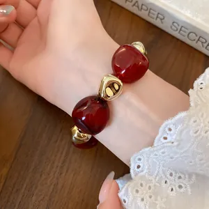 Detailed close-up view of a vintage irregular burgundy stained bead and gold metal bracelet