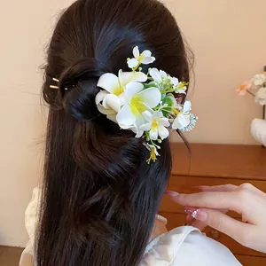 Détail d'une épingle à cheveux en tissu avec fleurs sur des cheveux ondulés noirs