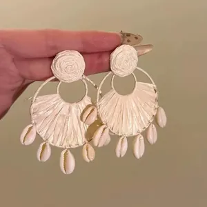 Hand-held close-up showing intricate raffia weaving and natural cowrie shell details