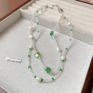 Close-up of handmade beaded necklace with green flower charms and a heart-shaped pendant.