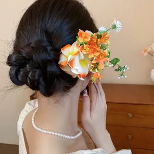 Vue détaillée de fleurs en tissu colorées sur une épingle à cheveux portée en chignon