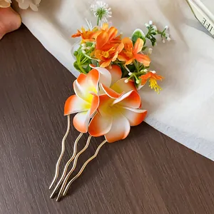 Détail d'une élégante fourche à cheveux florale orange et blanche avec tiges dorées