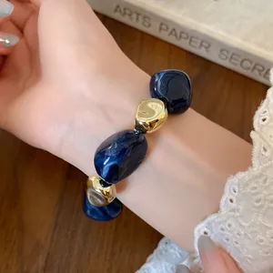 Close-up view of irregular marbled blue resin and metallic gold beads on a vintage bracelet
