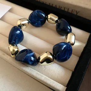 Close-up detail of blue marbled beads and gold irregular accents on a chic bracelet.