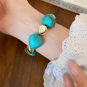 Close-up of irregular marbled turquoise and gold bead bracelet on woman's wrist, vintage style