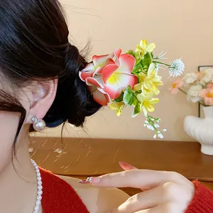 Vue détaillée de l'épingle à cheveux florale en tissu dans un chignon avec perles élégantes
