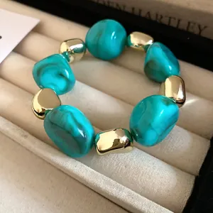 Macro close-up of irregular marbled turquoise and polished gold-tone metal beads necklace