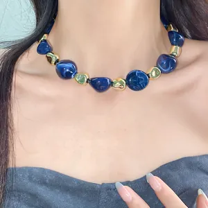 Close-up of irregular blue marbled and gold metallic beads on a vintage choker necklace