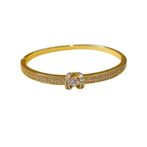 Bracelet jonc ovale doré à l'or fin avec cristaux micro-pavés et pierre centrale.