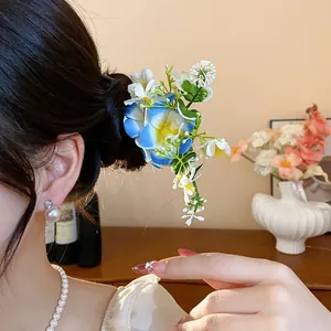 Gros plan d'un élégant pic à cheveux avec fleurs en tissu bleu et blanc dans un chignon.