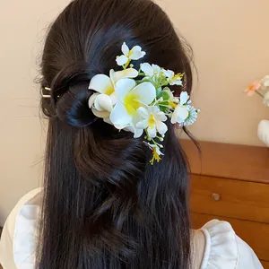 Vue détaillée d'une élégante épingle à cheveux fleur blanche sur des cheveux coiffés.