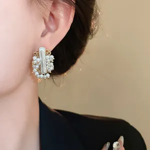 Primo piano di un orecchino vintage con perle finte indossato, elegante design color oro