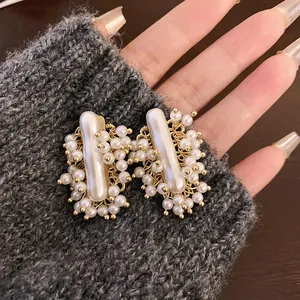 Eleganti orecchini retrò francesi con perle artificiali e filo dorato su maglia grigia