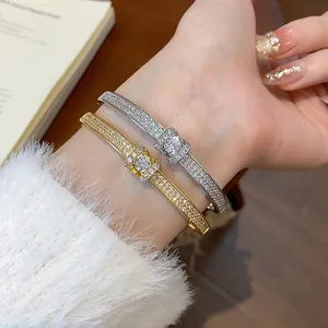 Gros plan de bracelets ovales dorés et argentés sertis de diamants au poignet