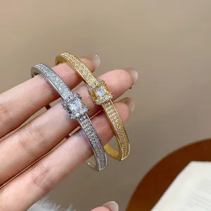 Détail de joncs ovales élégants plaqués or et argent, incrustés de diamants pavés.