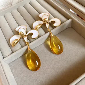 Close-up of vintage white flower earrings with translucent amber teardrop pendants