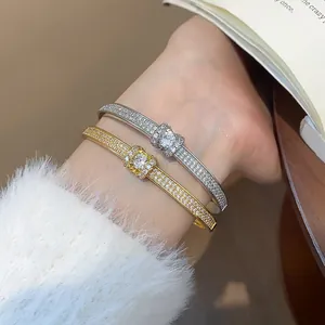 Gros plan de bracelets joncs plaqués or et argent avec cristaux pavés étincelants.