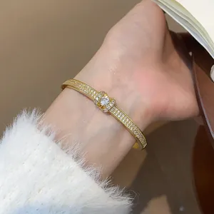 Gros plan d'un jonc diamanté plaqué or avec un design de boucle centrale.