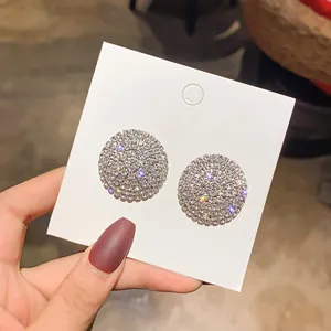 Elegant round stud earrings fully paved with sparkling clear crystals on a white display card