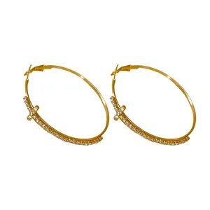 Elegantes pendientes de aro dorados con un diseño de cruz engastado con diamantes.