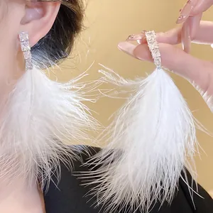 Detail of elegant white feather tassel earrings with sparkling square zircons.