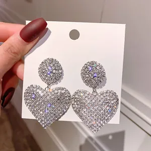 Close-up of sparkling full rhinestone heart drop earrings with vintage silver needle