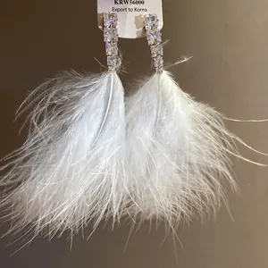 Detail view of elegant white feather tassel earrings with sparkling zircon stones.