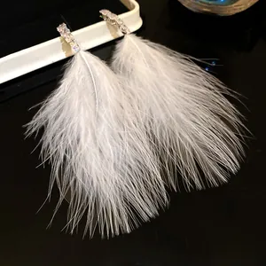 Close-up detail of soft white feather tassels and sparkling zircon studs on earrings
