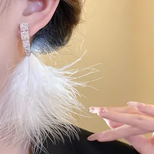 Close-up of elegant silver earrings featuring cubic zirconia and white feather tassels