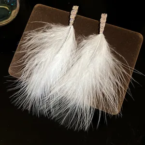 Detailed macro view of elegant white feather earrings with cubic zirconia studs.