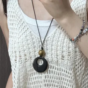 Detailed view of an ethnic style long necklace featuring a black resin ring pendant