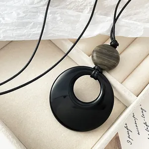 Ethnic style long necklace featuring a large black resin ring and striped bead pendant
