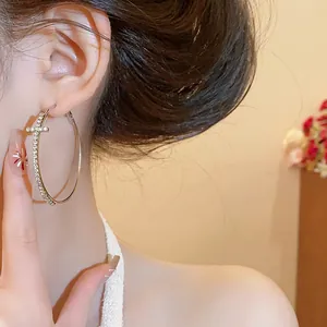 Vista detallada de pendientes de aro de lujo con un diseño de cruz de diamantes brillante
