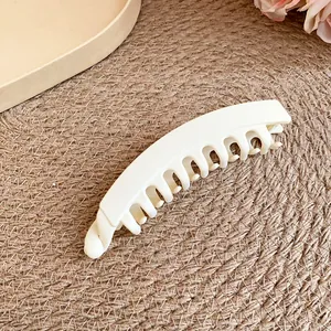 Gros plan d'une pince à cheveux banane en acrylique mat blanc crème sur tapis