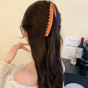Gros plan d'une pince à cheveux banane orange mate portée par un mannequin de dos.