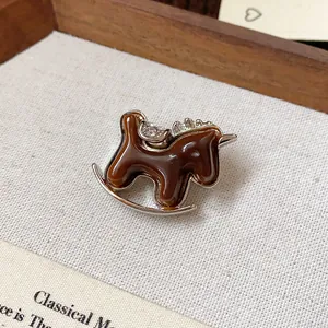 Macro detail showing the brown resin and rhinestone accents of a rocking horse brooch
